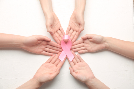 Female hands holding pink ribbon on white background. Breast cancer awareness conceptの写真素材