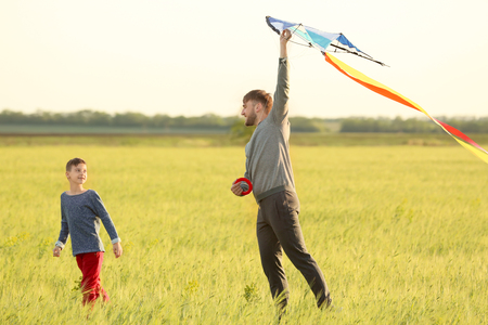 Happy father and son flying kite in the fieldの写真素材