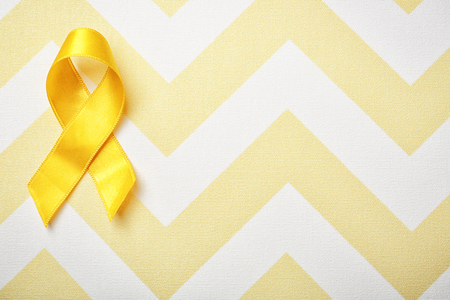 Yellow ribbon on color background. Cancer conceptの写真素材