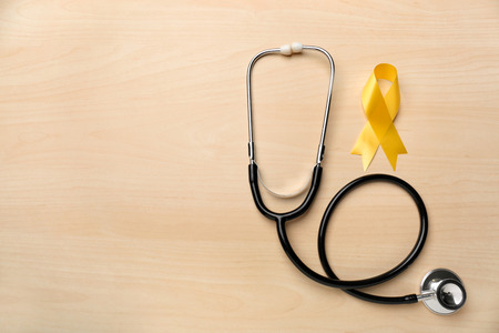 Yellow ribbon and stethoscope on light background. Cancer conceptの写真素材