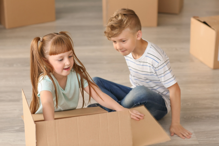 Cute children unpacking box after moving into new houseの写真素材