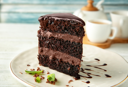 Plate with piece of delicious chocolate cake on light table