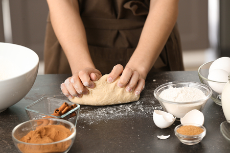 Woman kneading dough for cinnamon buns at tableの写真素材