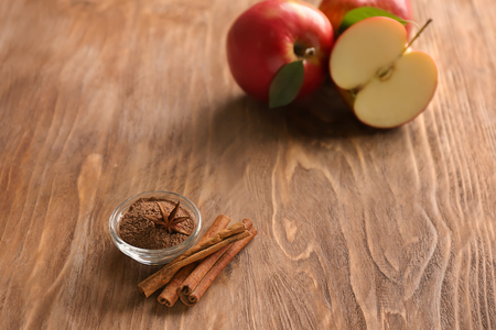 Bowl with cinnamon and fresh apples on wooden tableの写真素材