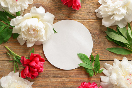 Beautiful peony flowers with blank card on wooden backgroundの写真素材