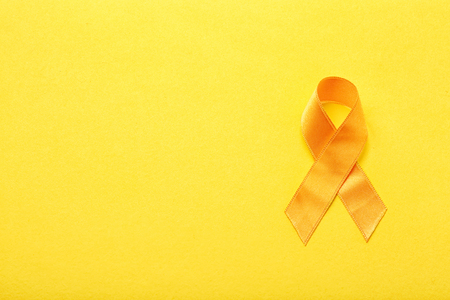 Yellow ribbon on color background. Cancer conceptの写真素材