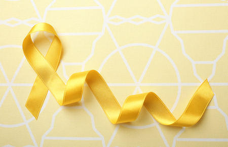 Yellow ribbon on color background. Cancer conceptの写真素材