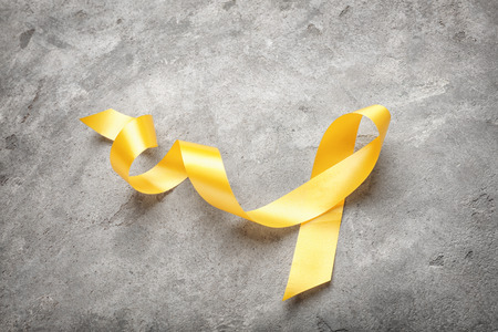 Yellow ribbon on grey background. Cancer conceptの写真素材