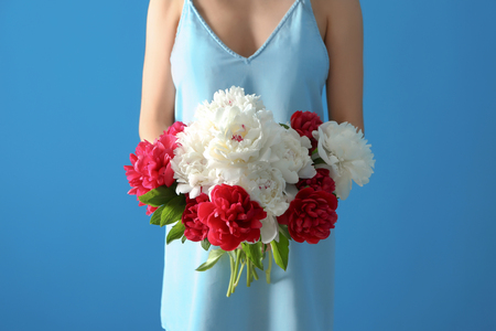 Young woman holding beautiful peonies on color backgroundの写真素材