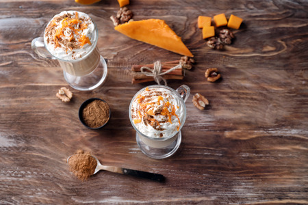 Glass cups of latte with pumpkin and cinnamon on wooden tableの写真素材