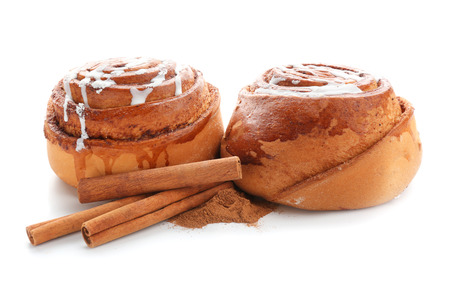 Tasty sweet buns with cinnamon sticks and powder on white backgroundの写真素材