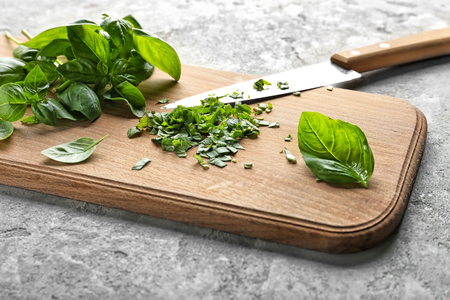 Wooden board with fresh green basil leaves on grey textured backgroundの写真素材
