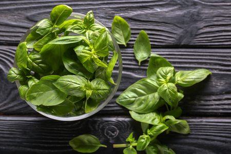Bowl with fresh green basil leaves on dark wooden backgroundの写真素材