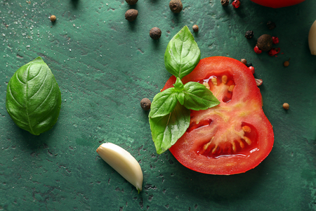 Fresh green basil leaves with tomato and spices on color backgroundの写真素材