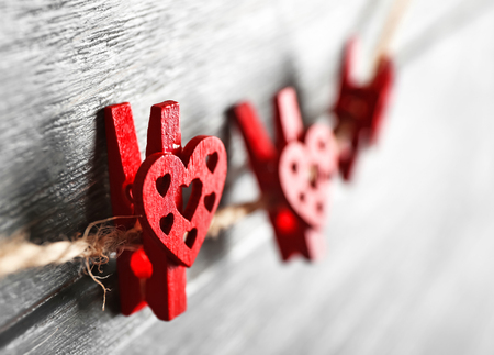 Pegs with hearts hanging on rope against wooden background, closeupの写真素材
