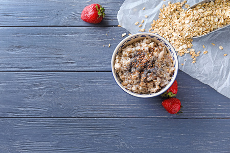 Bowl with tasty oatmeal on wooden background