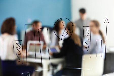 View of business meeting through transparent board with drawn diagramの写真素材