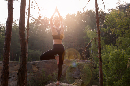 Beautiful young woman practicing yoga outdoors in morningの写真素材