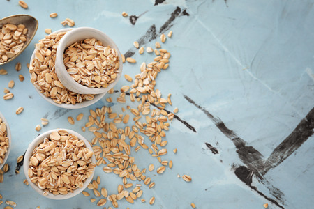 Bowls with raw oatmeal on color backgroundの写真素材