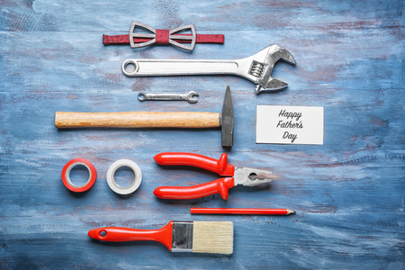 Card with text "Happy Father's Day", bow tie and set of tools on wooden backgroundの写真素材