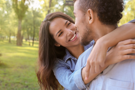 Happy African-American couple in park on spring dayの写真素材
