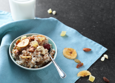 Bowl with tasty oatmeal and spoon on tableの写真素材