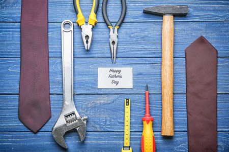 Card with text "Happy Father's Day", male ties and set of tools on wooden backgroundの写真素材