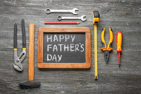 Chalkboard with text "Happy Father's Day" and set of tools on wooden backgroundの写真素材