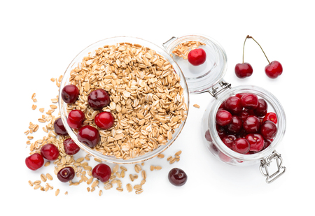 Bowl with raw oatmeal and fresh cherries in jar on white backgroundの写真素材