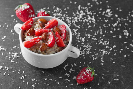 Bowl with tasty oatmeal, almonds and strawberry on grey backgroundの写真素材
