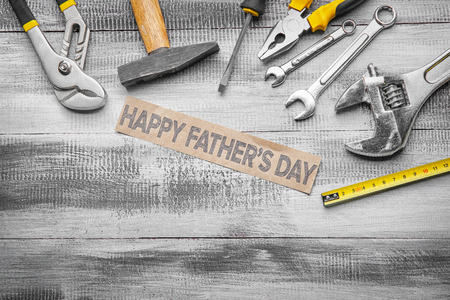 Sheet of paper with text "Happy Father's Day" and set of tools on wooden backgroundの写真素材