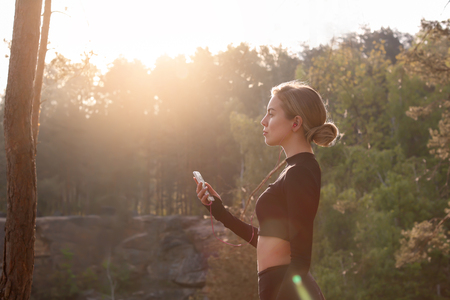Sporty young woman listening to music outdoors in morning
