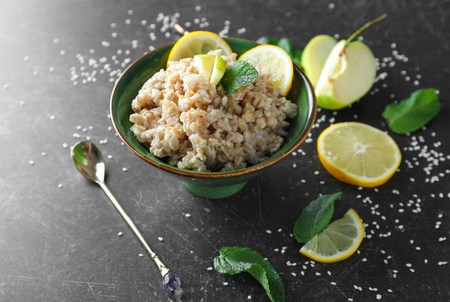 Bowl with tasty oatmeal, fresh apple and sliced lemon on grey backgroundの写真素材