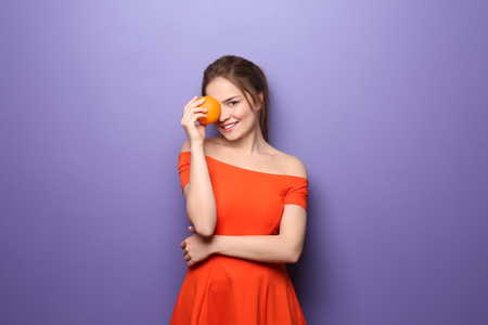 Beautiful young woman with citrus fruit on color backgroundの写真素材