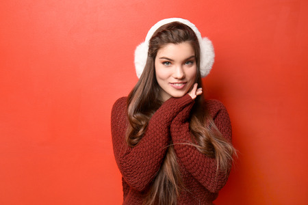 Beautiful young woman in warm clothes on color backgroundの写真素材