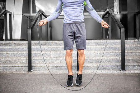 Sporty young man jumping rope outdoorsの写真素材