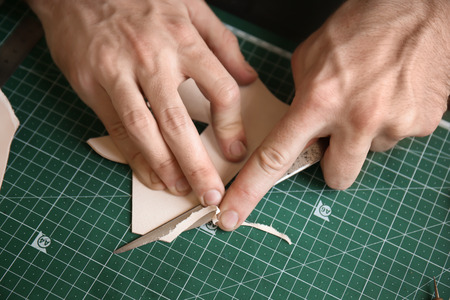 Man working with piece of leather at factory, closeup