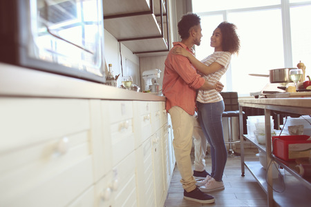Young African-American couple hugging in kitchenの写真素材