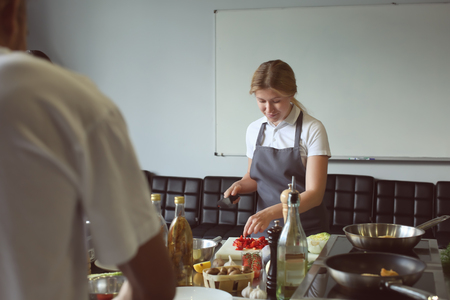 Young woman cooking in restaurant kitchen during cooking classesの写真素材