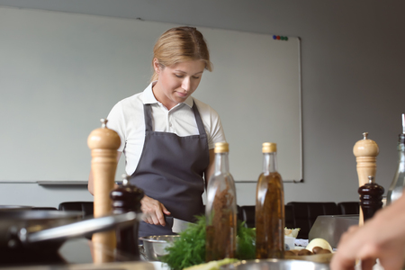 Young woman cooking in restaurant kitchen during cooking classesの写真素材