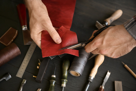 Man cutting piece of leather in workshop, closeup