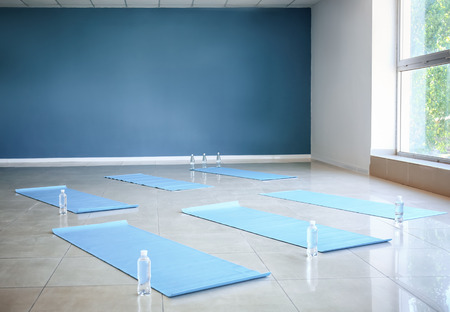 Yoga mats and bottles of water on floor in gymの写真素材