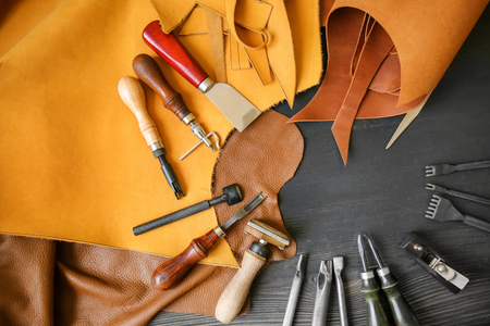 Leather with craft tools on dark wooden backgroundの写真素材