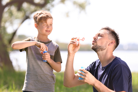 Little boy and his dad blowing soap bubbles outdoorsの写真素材