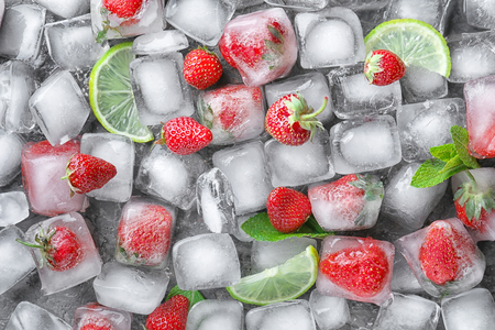 Ice cubes with strawberries and lime slices on dark background, top viewの写真素材