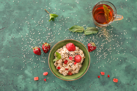Bowl with tasty oatmeal and strawberry on color backgroundの写真素材
