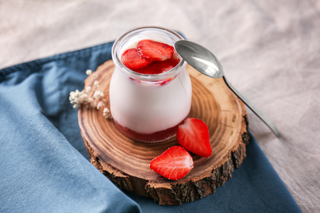 Glass jar with tasty yogurt and strawberries on tableの写真素材