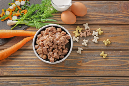Bowl with pet food and natural products on wooden backgroundの写真素材