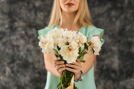 Young woman with beautiful flowers on grunge backgroundの写真素材