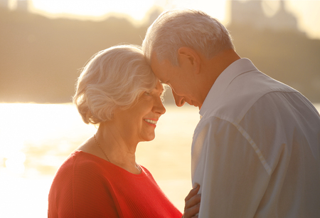 Happy mature couple on riverside at sunset